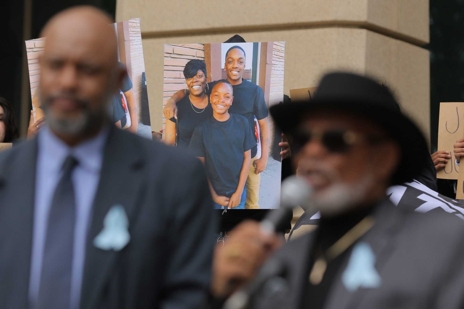 A photo of Jor&#039;Dell Da&#039;Shawn Richardson (in front) with his family is shown behind Dr. Thomas S. Mayes of The Greater Metro Denver Ministerial Alliance as he speaks.