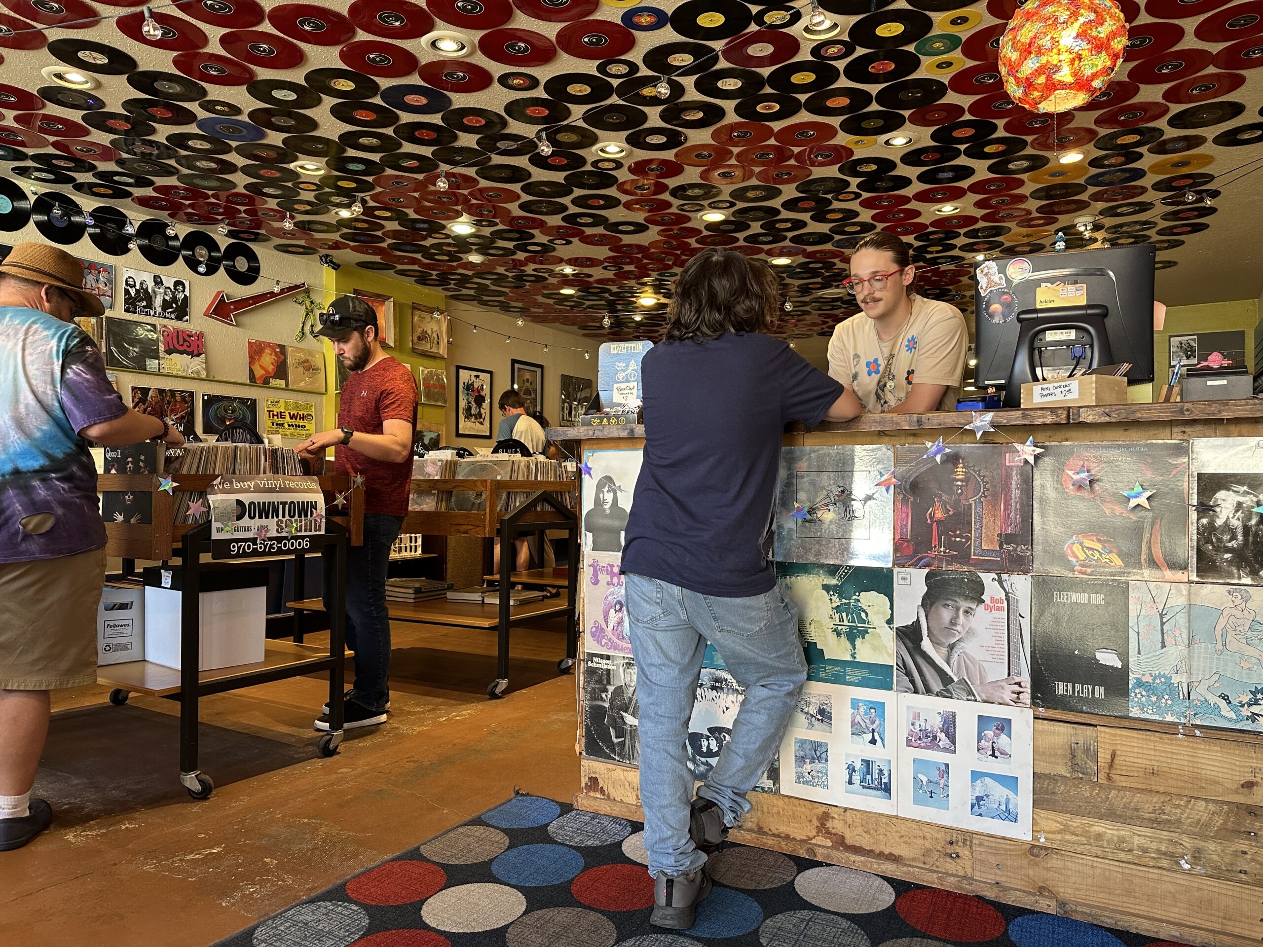 From behind the counter, Ben Jankow, whose parents own the Downtown Sound record shop in Downtown Loveland, talks with his brother, Nicholas Jankow.