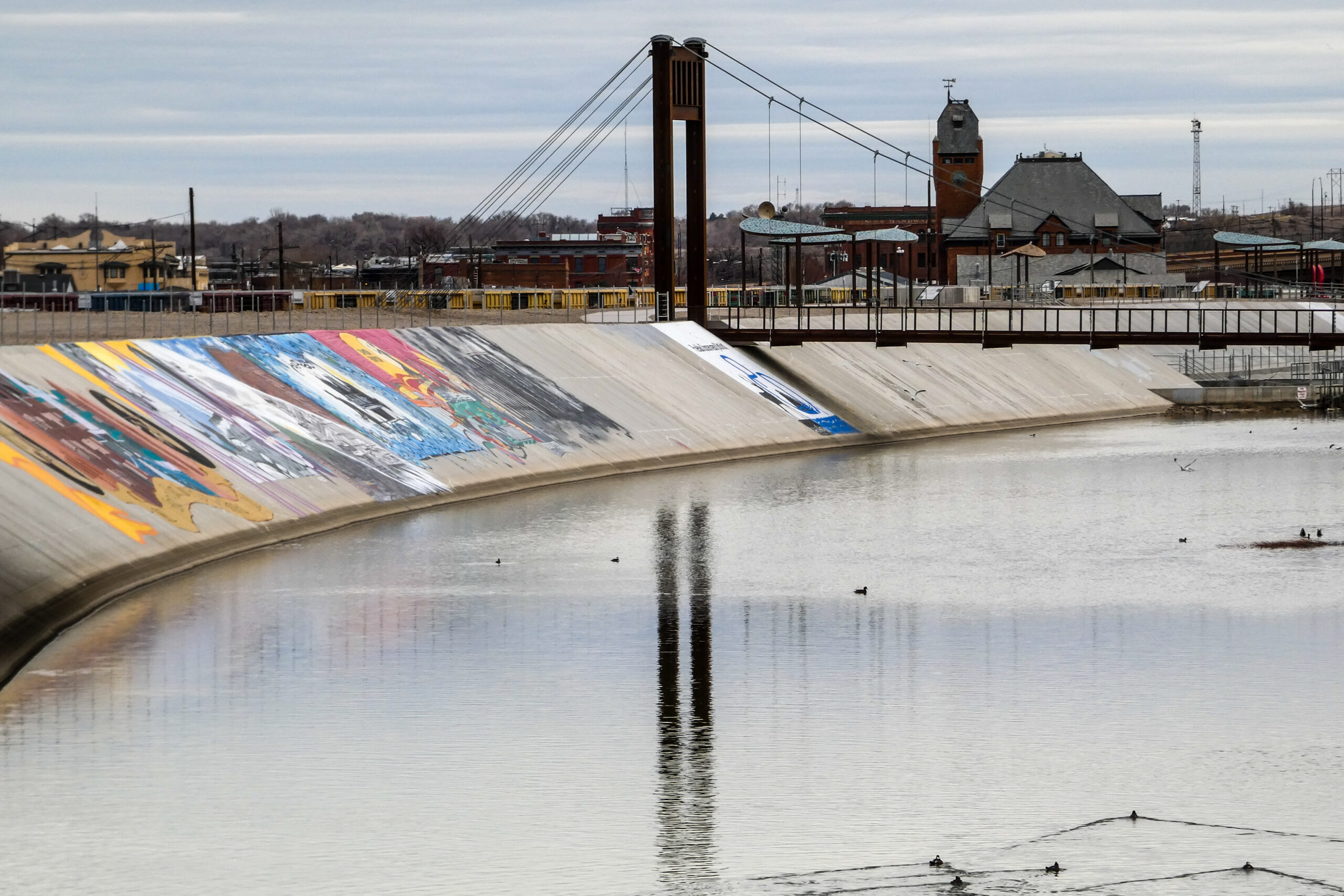 Colorado history themed murals are among these painted on the Arkansas River levee near a pedestrian bridge in Pueblo. (Dec. 28, 2022)